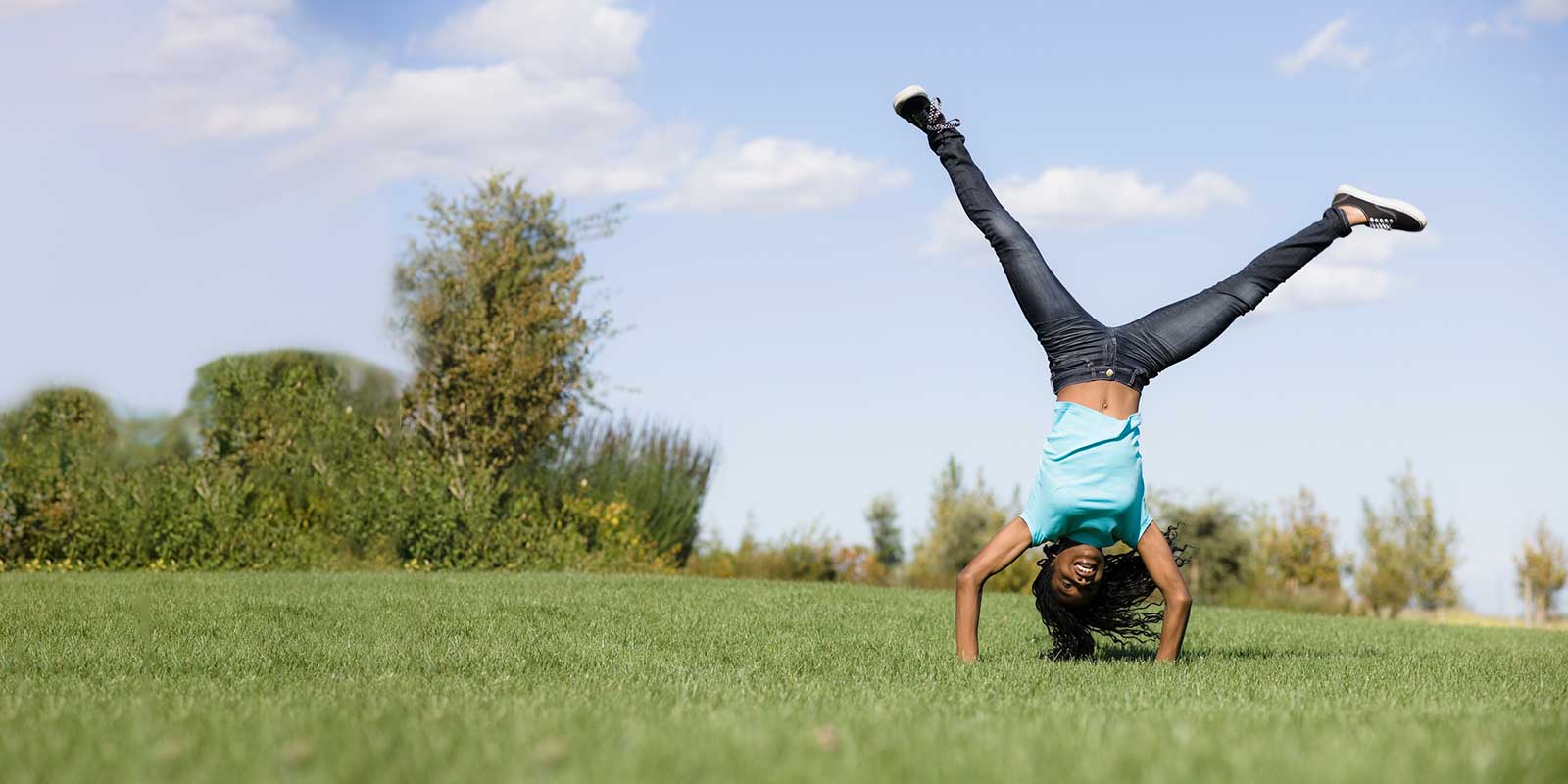 Young girl doing handstand in a field