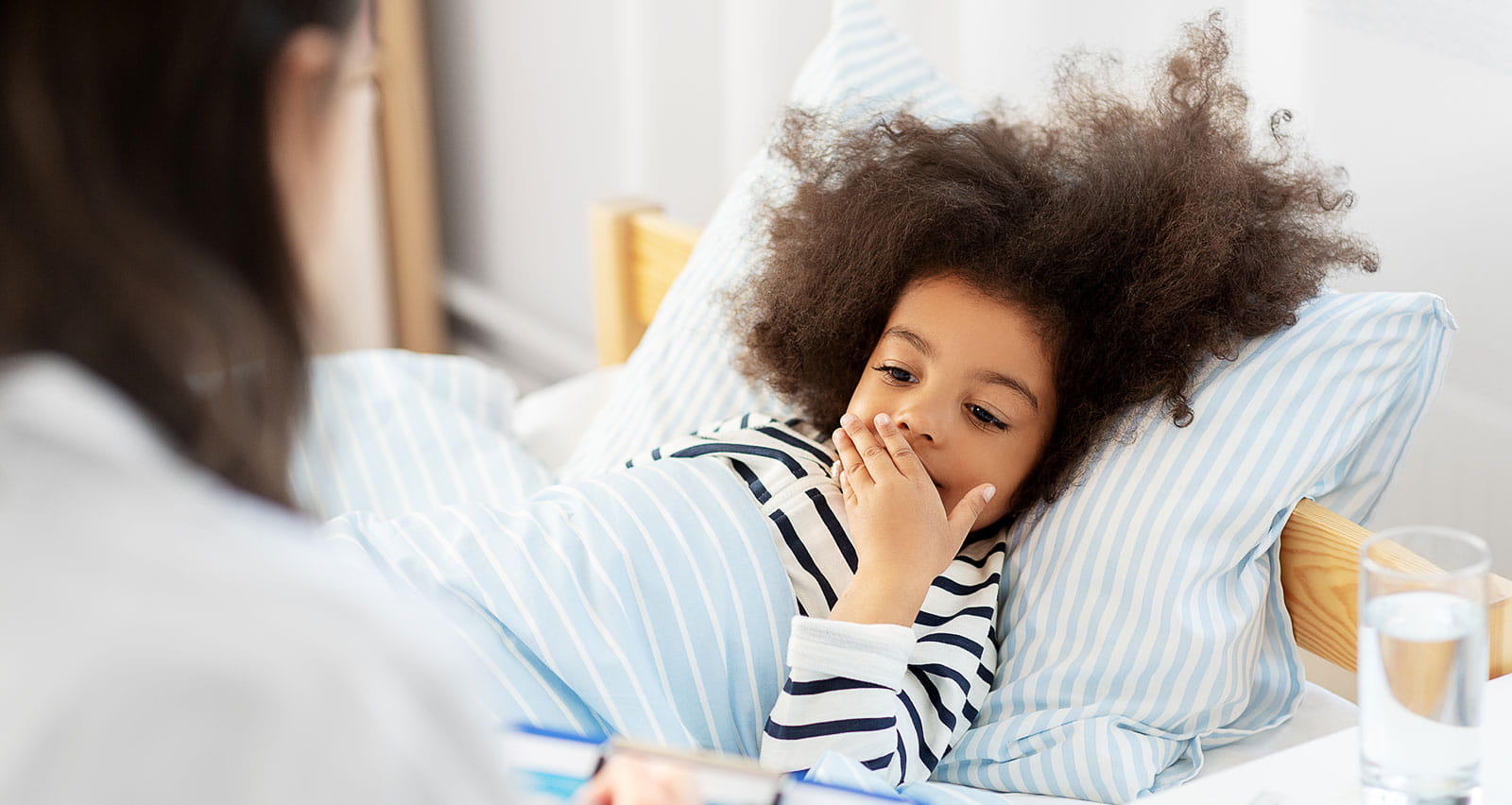 A girl yawns in bed as a provider updates her notes