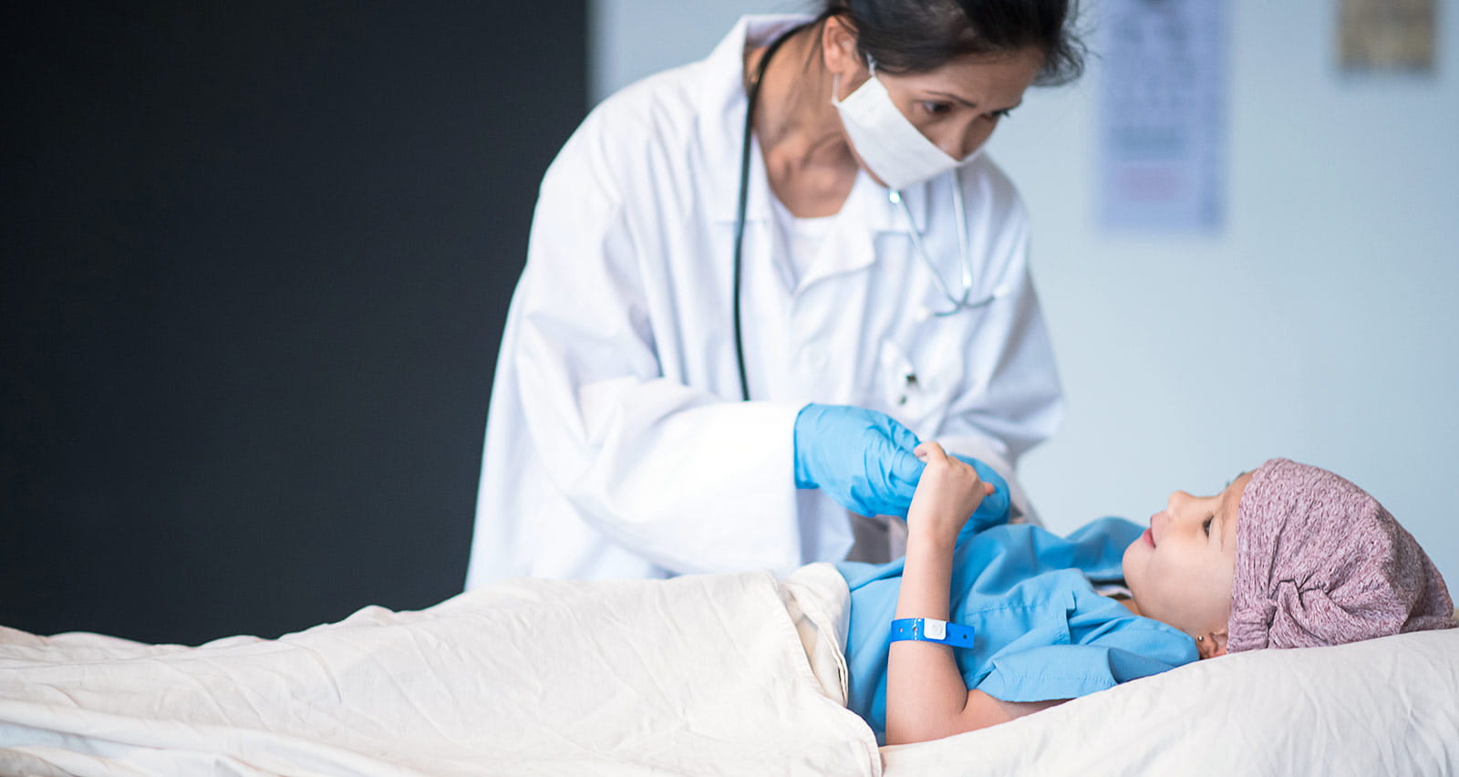 A female doctor checks on a young cancer patient