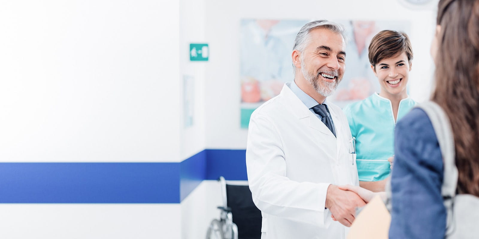 Doctor speaking with patient and shaking hands in the hallway.