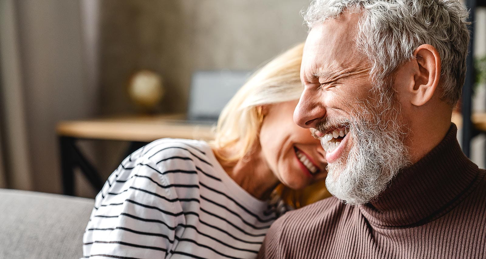 A middle-aged couple embraces on their sofa