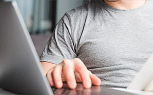A positive, optimistic young man at home using a laptop computer and holding documents