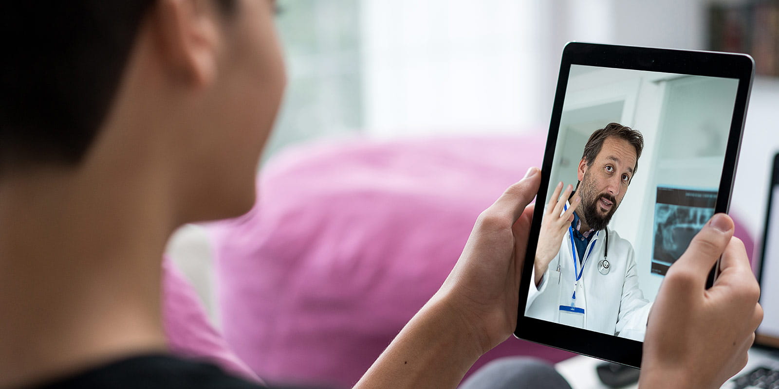 Young person receiving consultation from doctor online using a tablet computer