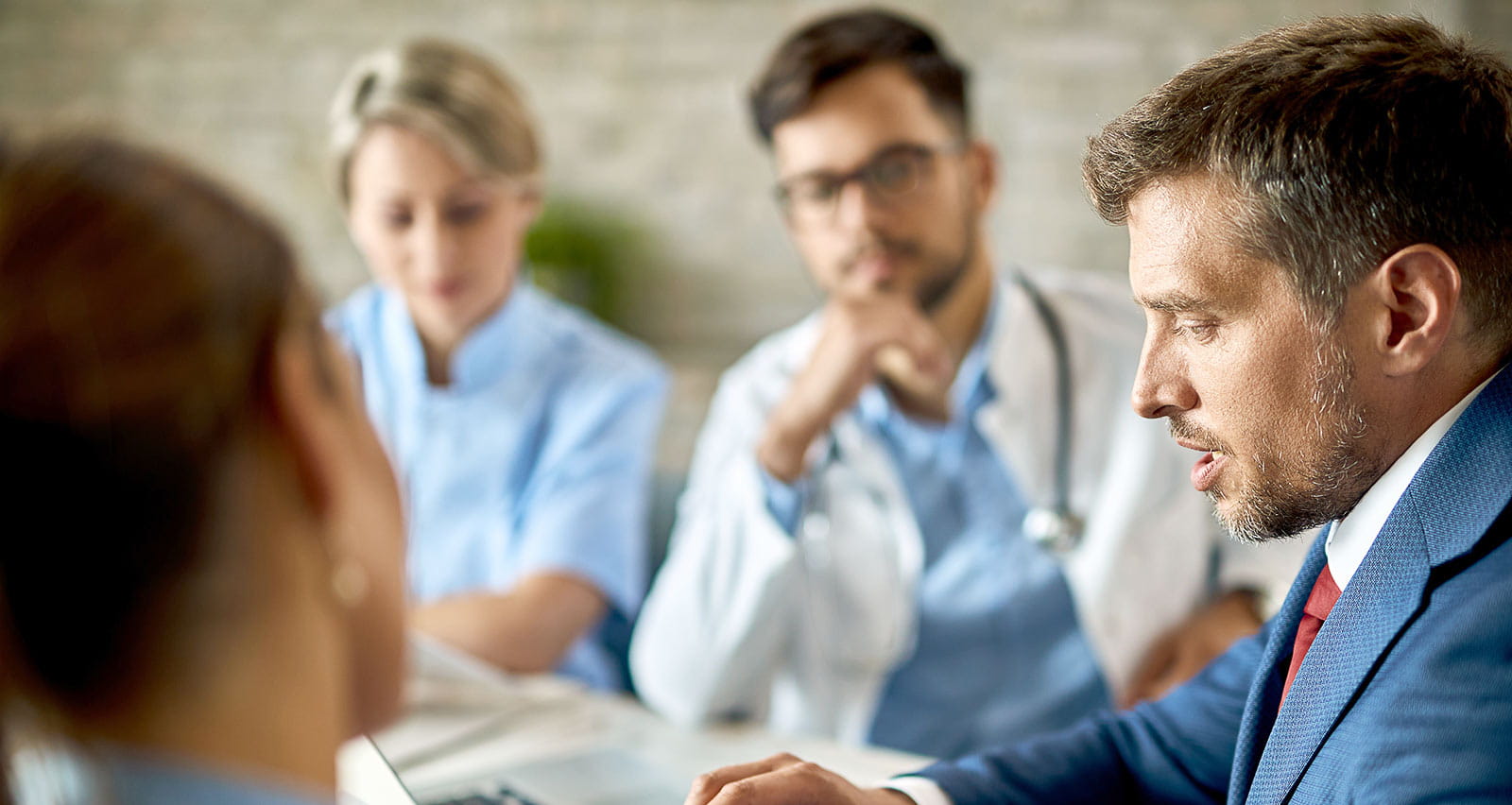 A businessman and healthcare workers analyzing documents during a meeting in the office