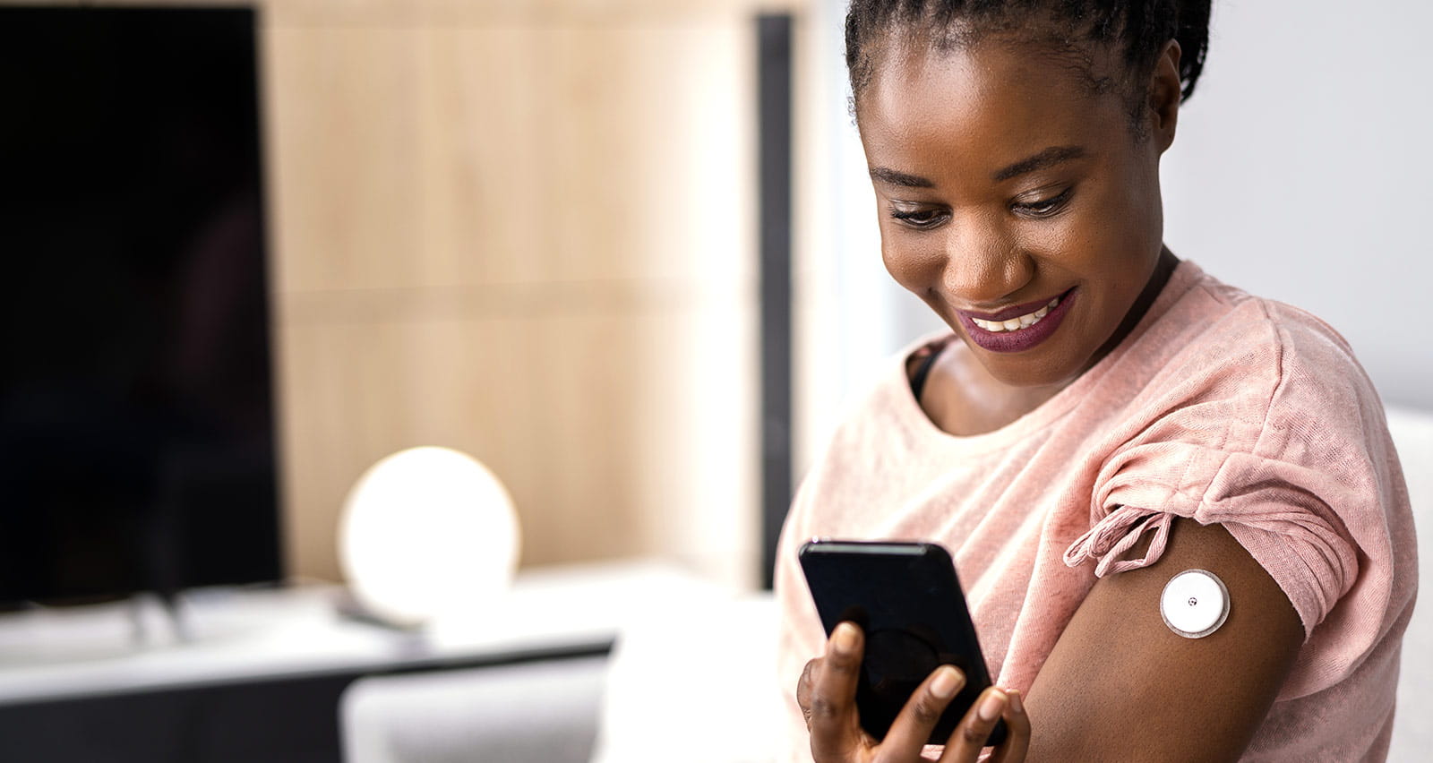 A woman testing glucose level with continuous glucose monitor on mobile phone