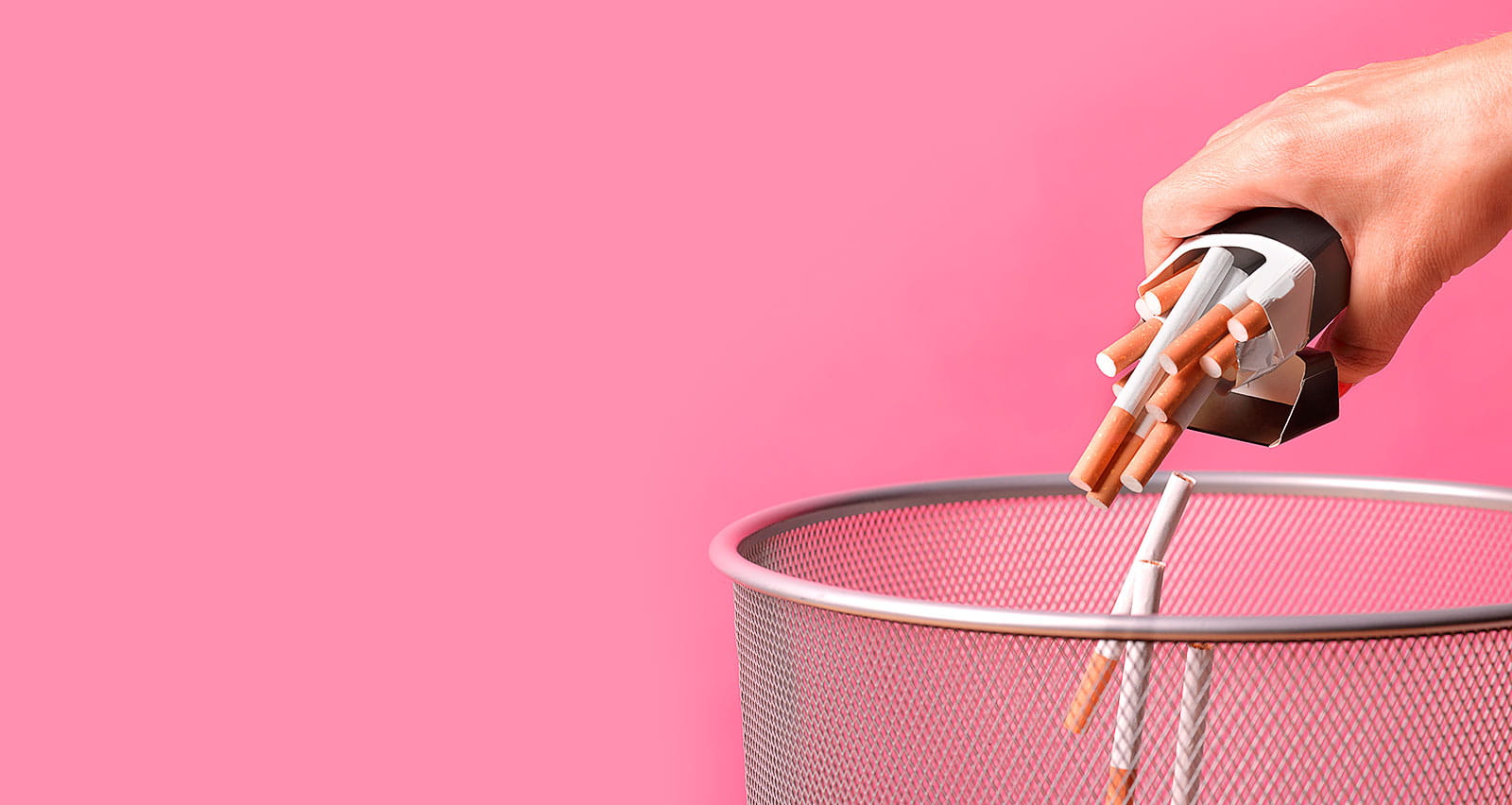 A woman throwing a pack of cigarettes away in a bin