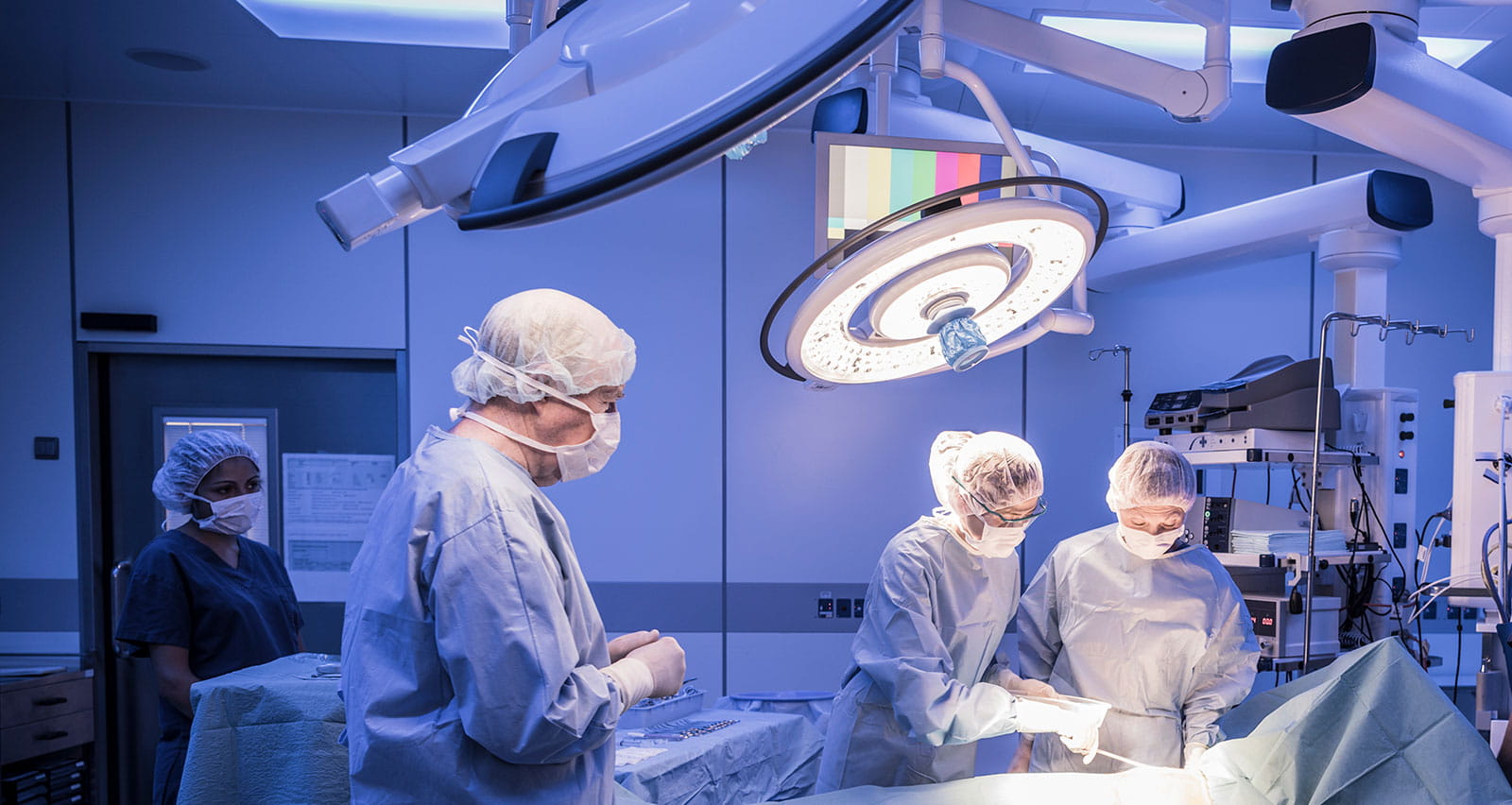 A team of four doctors in an operating room attending to a patient on the table
