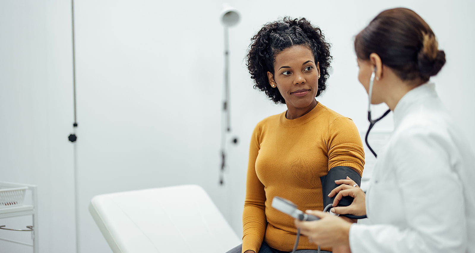 Doctor measuring the blood pressure of a smiling woman as a part of a medical exam