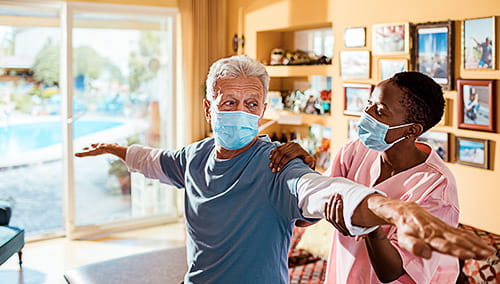 A young female caregiver gives physical therapy to her patient