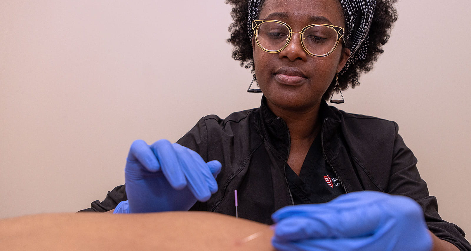 Joan Odhiambo, LAc performs acupuncture on a patient at UH Connor Whole Health