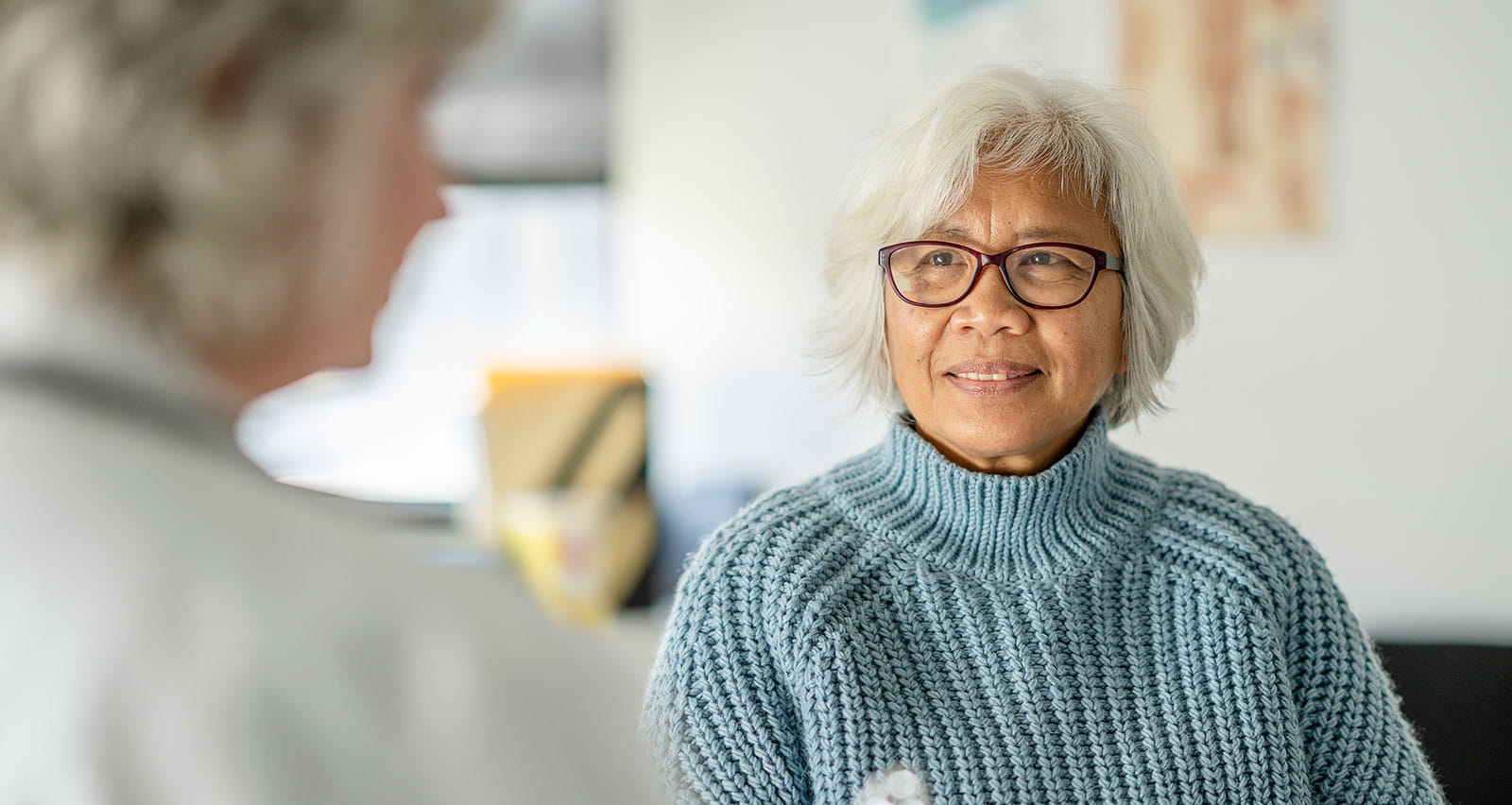 A female doctor holds out a clipboard during an appointment with her senior patient