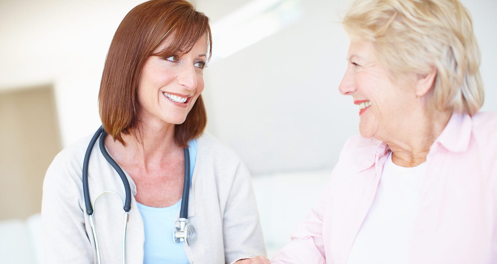 Mature nurse has a friendly conversation with an elderly female stroke patient