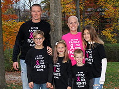 A smiling Alison Berger poses with her happy family in an autumnal setting