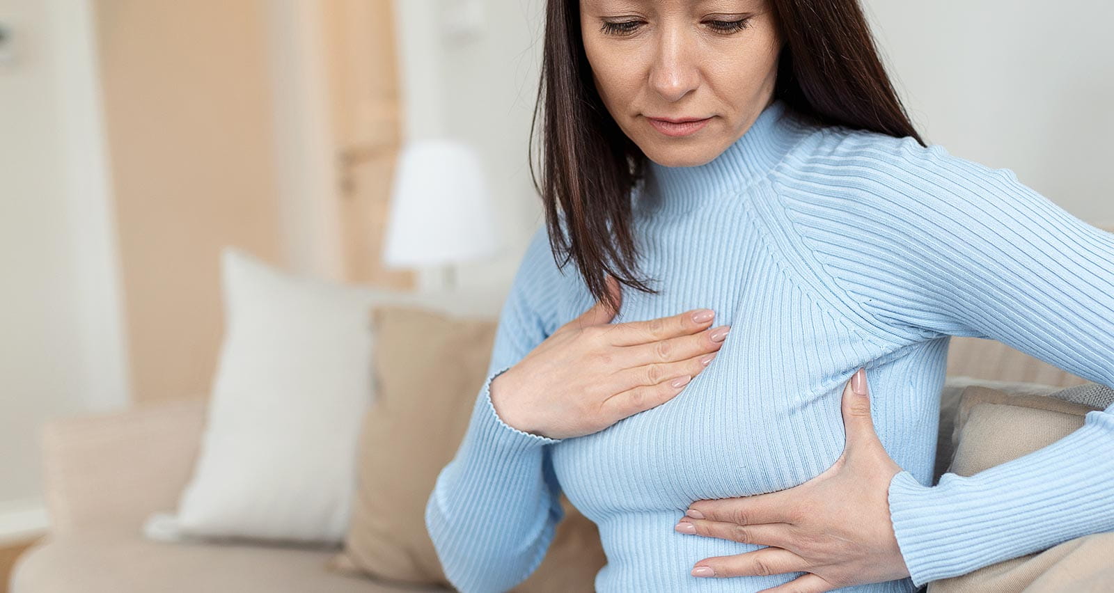 A middle-aged woman checking lumps on her breast for signs of breast cancer