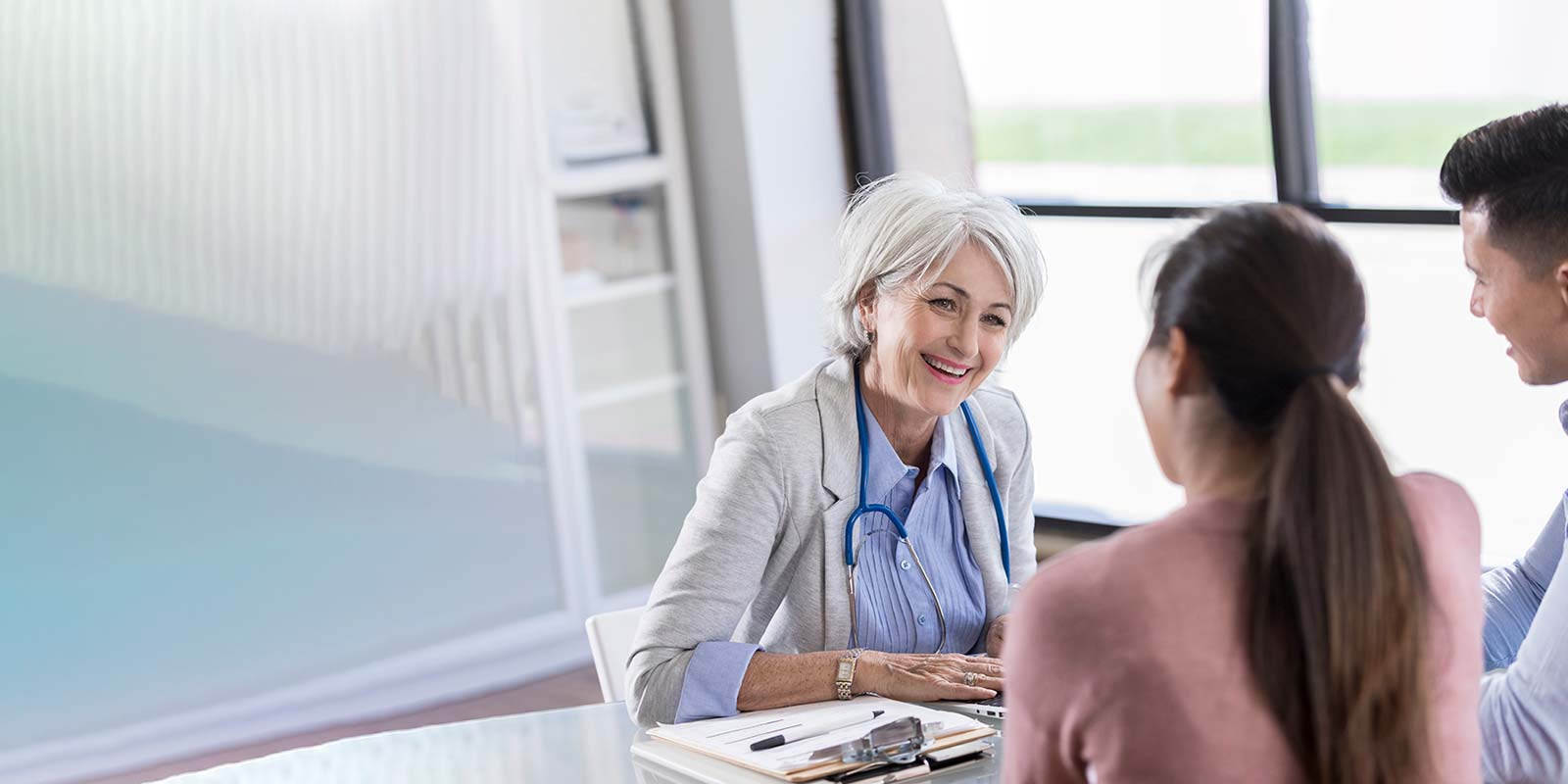Female doctor talks with young couple in her office