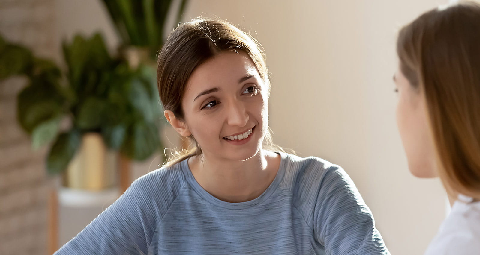 A smiling young woman listening to her doctor