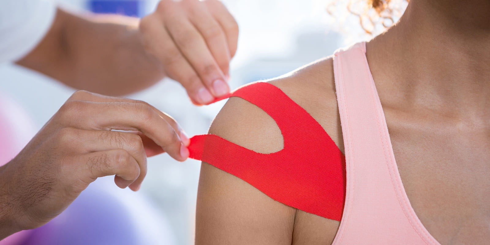 Medical Staff taping female athlete's shoulder.
