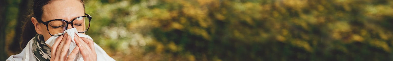 Woman sneezing outdoors.