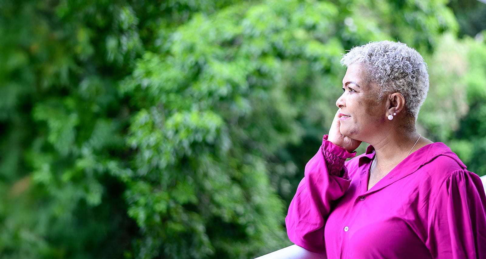 A smiling middle-aged woman looking away to the trees