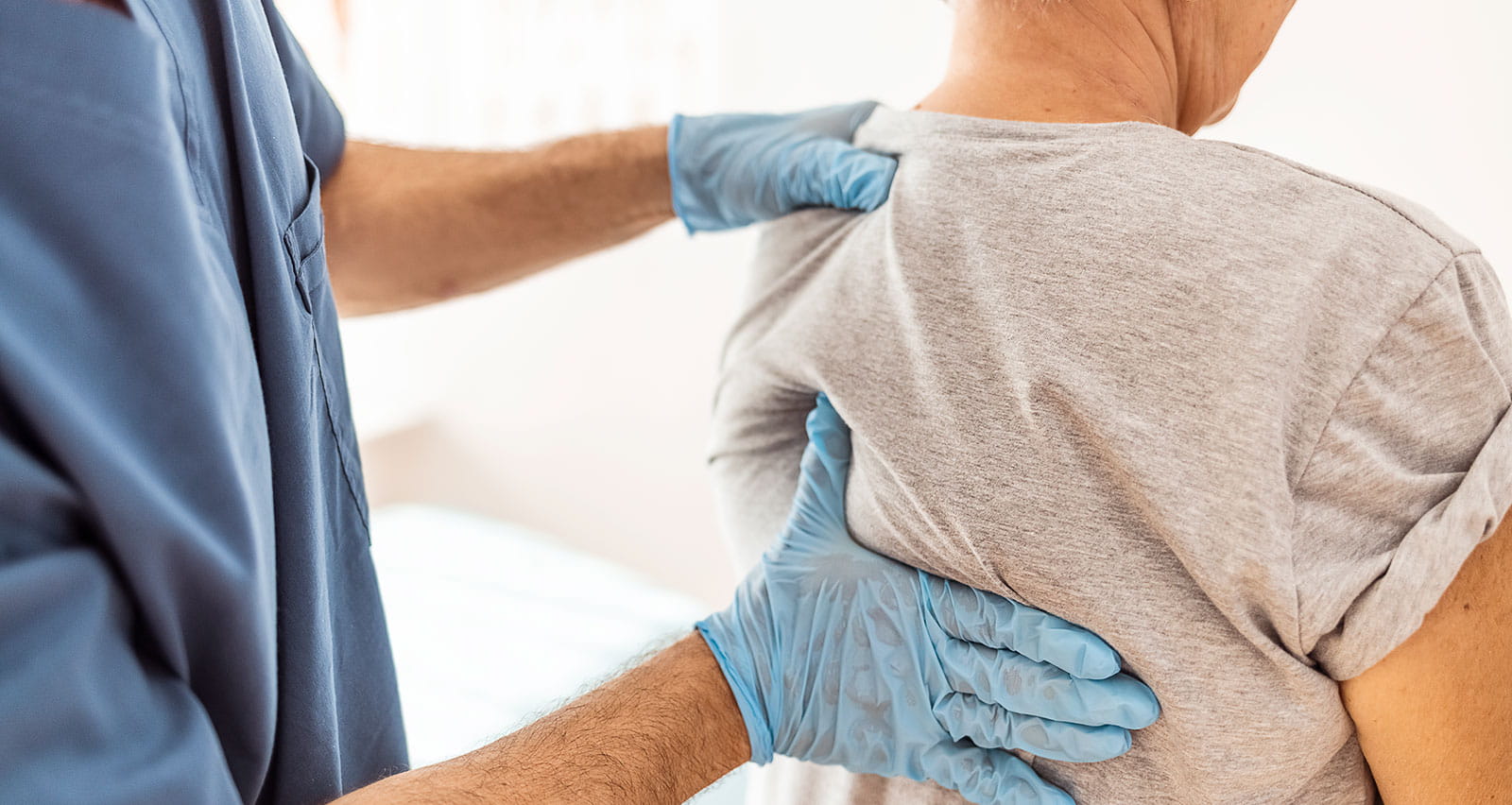 Senior adult female patient having back examined by male provider