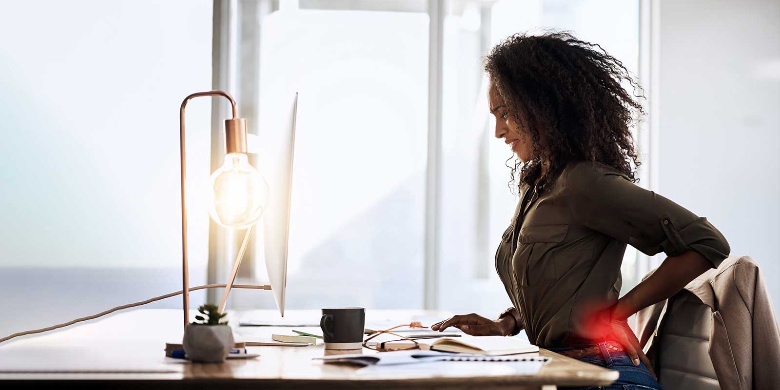 Woman sitting at her desk experiencing low back pain