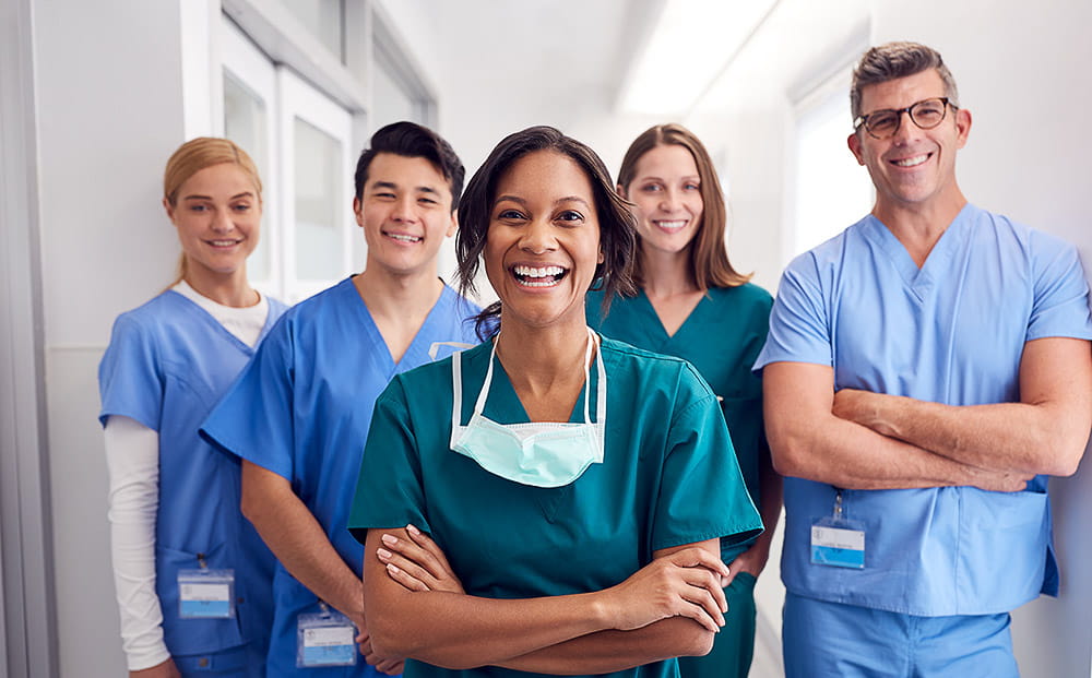 Portrait of laughing multi-cultural medical team standing in hospital corridor